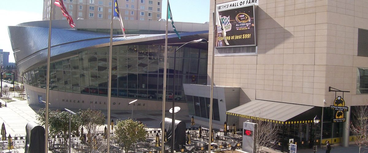 Exterior of the NASCAR Hall of Fame, showing its curved glass and metal facade in Uptown Charlotte