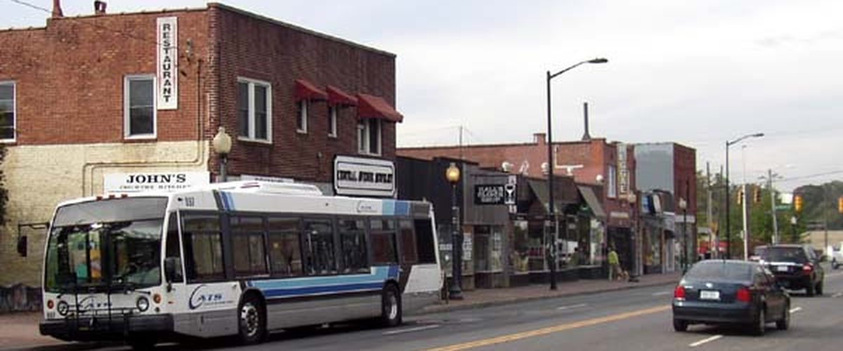 Street scene in Plaza Midwood, Charlotte, showing a CATS bus and small shopfronts along Central Avenue